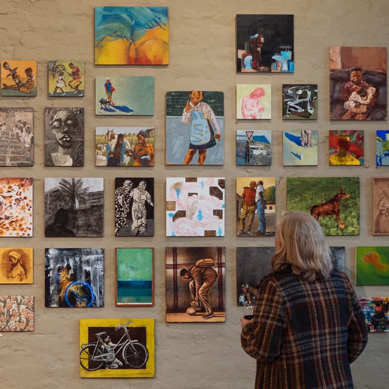 person with wine glass looking at art