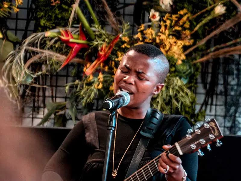 A lady signing and playing the guitar
