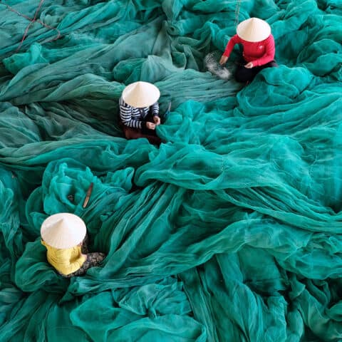three people mainng a large green sheet